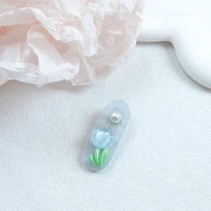 Detailed macro view of a light blue tulip hair clip featuring a white pearl accent