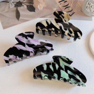 Detailed view of three large acetate hair claws with elegant marble ink patterns