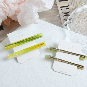 Detailed macro view of long acetate hair clips with yellow and green gradient texture