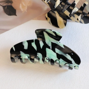 Close-up of marble texture acetate hair claw clip with mint green and black patterns