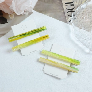 Detailed macro view of four translucent gradient resin hair clips on white card packaging