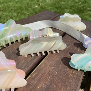 Close-up of wavy cloud-shaped acetate hair claws with iridescent pearl finish and sturdy spring