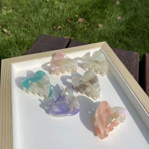 Set of six colorful heart-shaped acetate hair claws displayed in a wooden frame