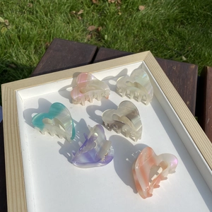 Close-up of heart-shaped acetate hair claws in assorted pastel marble colors on a tray