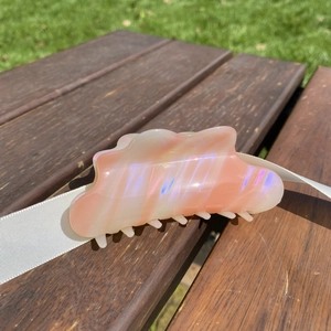 Macro shot of cloud-shaped wavy hair claw clip with colorful iridescent pearlescent texture