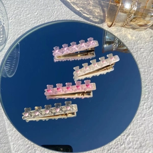 Detail showing four resin bear hair clips with pink hearts on a mirror surface