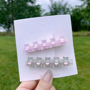 Detail of candy-colored resin bear hair clips in purple and blue on a green lawn