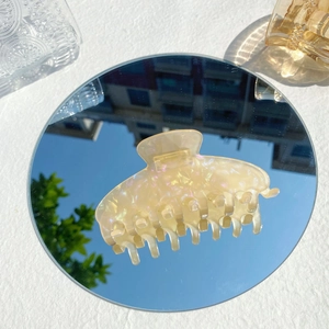 Detailed close-up of large iridescent acetate hair claw clip with mother of pearl luster