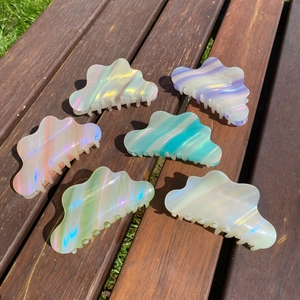 Cloud shaped acetate hair claw clips set in iridescent macaron colors on wood