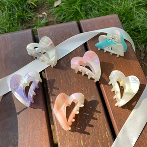 Set of 6 heart-shaped iridescent acetate hair claws in pastel colors on wooden surface
