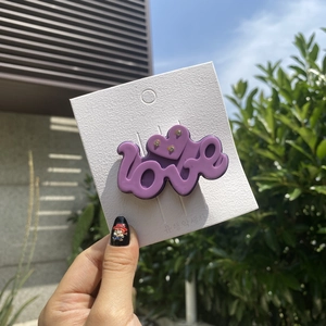 Detailed view of purple acetate LOVE hair clip with sparkling rhinestones decoration