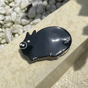 Close-up of a glossy black pig hair claw clip made of acrylic on a stone surface