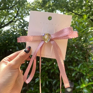Close-up of pink ribbon bow hairclip with heart-shaped portrait cameo on display card