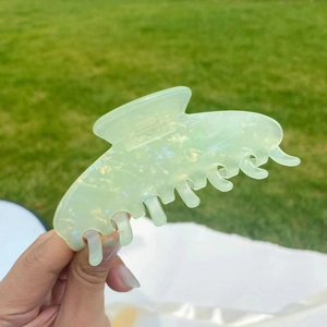Detailed macro of a mint green marbled cellulose hair claw clip with golden glitters