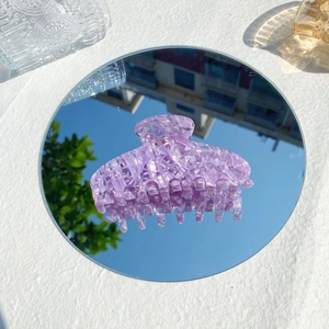 Detailansicht der großen Haarspange aus lila Acetat, gespiegelt auf einem runden Spiegel