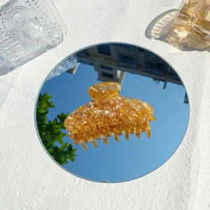 Makro-Detail der bernsteinfarbenen Haarklammer mit Schildpatt-Muster auf Spiegelglas