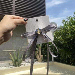 Detailed macro of a grey ribbon bow hair clip with a blue gradient pearl heart center