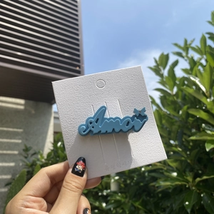 Detail of blue acetate hair clip with Amor lettering and a small sparkling star rhinestone