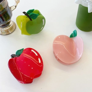Détail de pinces à cheveux en acétate en forme de pomme et pêche sur une table