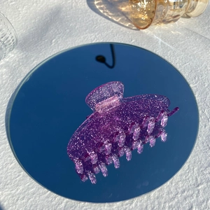 Macro shot of purple translucent glitter hair claw clip on a mirror with reflection