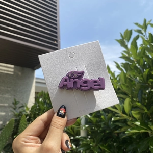 Detail of purple Angel hair clip with rhinestones displayed on white card in daylight