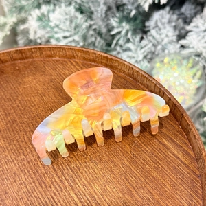 Macro shot of colorful large acetate hair claw clip with iridescent jelly finish on wood