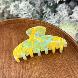 Detail of large acetate hair claw clip featuring blue and yellow marble pattern texture