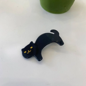 Detail einer schwarzen Katzen-Haarklammer aus Acetat mit eleganten goldenen Gesichtszügen