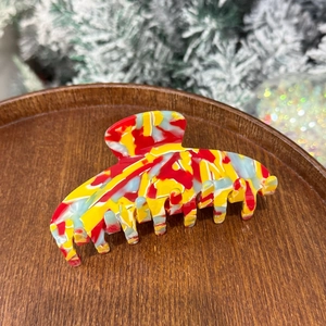 Iridescent mermaid acetate hair claw clip with colorful marble pattern on wooden tray