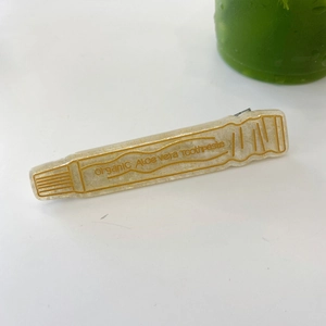 Detail der kreativen Haarspange in Zahnpastaform mit Goldglitzer und organischem Text