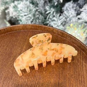 Detailed view of amber marble texture on large hair claw clip in a wooden tray