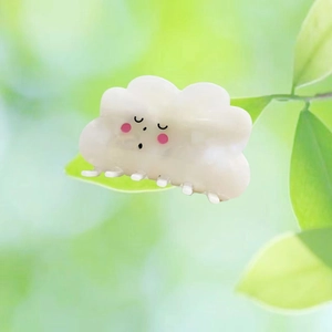 Cute white cloud hair claw clip with smiling face on a natural green leaf background