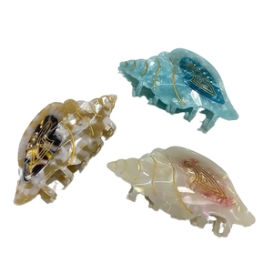 Conch shaped acetate hair claws with marble textures and gold metal accents in 3 colors