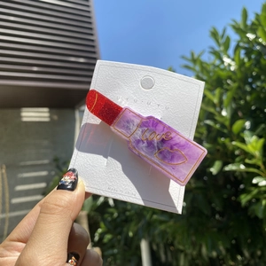 Haarklammer in Lippenstiftform mit glitzernder roter Spitze und lila Marmormuster