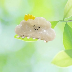 Close-up of white cloud hair claw clip with yellow sun detail and smiley face design