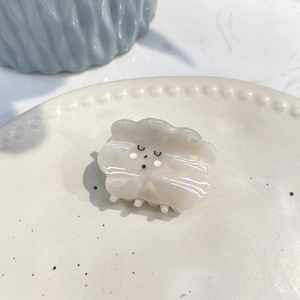 Close-up of a cute white cloud-shaped hair claw clip with a pearlescent acetate finish