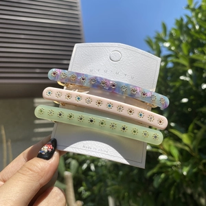 Detailansicht von drei Acetat-Haarspangen in Pastellfarben mit glitzernden Strassblumen
