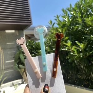 Nahaufnahme herzförmiger Acetat-Haarspangen mit Perlenakzenten in Pastellrosa und Blau
