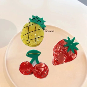 Detailed view of acetate fruit hair claws featuring pineapple strawberry and cherry designs