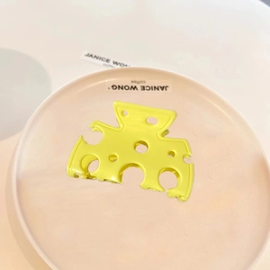 Cute yellow cheese-shaped acetate hair claw clip on a minimalist ceramic tray