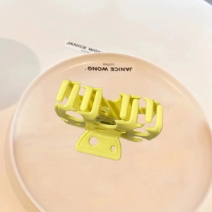 Pale yellow cheese style hair claw clip on pink plate with minimalist matte finish