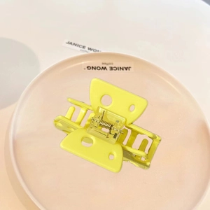 Sweet yellow cheese butterfly hair claw clip made of acetate on a pink ceramic plate
