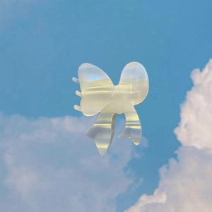 Pince à cheveux nœud irisante en acétate au fini perlé sur fond de ciel bleu clair