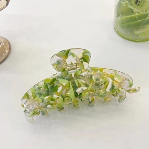 Detail showing translucent floral acetate hair claw clip with lime green and yellow patterns