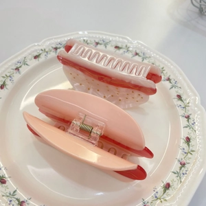 Macro shot of hot dog hair claws in pink and cream set on a floral ceramic plate