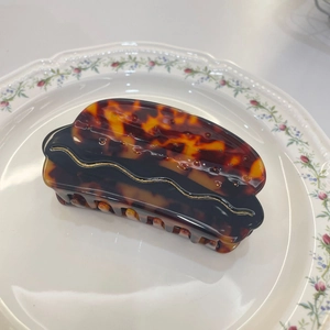 Creative acetate hot dog shaped hair claw clip with shell texture on ceramic plate