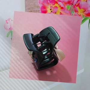 Vue détaillée d'une pince à cheveux noire brillante ornée de fleurs en cristaux colorés