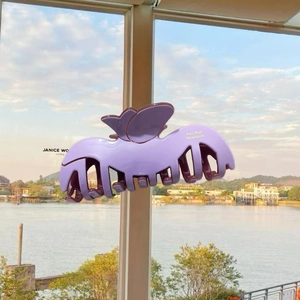 Detail of light purple acetate flower hair claw with butterfly design against scenic view