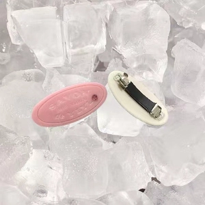 Detail of soap-shaped hair clip with SAVON engraving and pink rhinestone on ice background