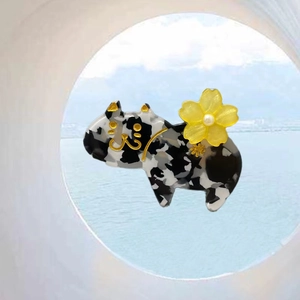 Detail einer schwarz-weiß gemusterten Katzenhaarklammer mit gelber Blume und Perle